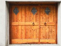 Porte de garage à deux portes avec fenêtres extérieures à l'extérieur recouvertes de bois